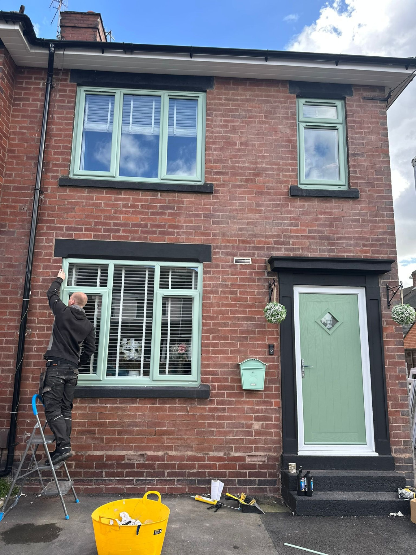 Chartwell green uPVC windows and matching composite door fitted to a red brick home