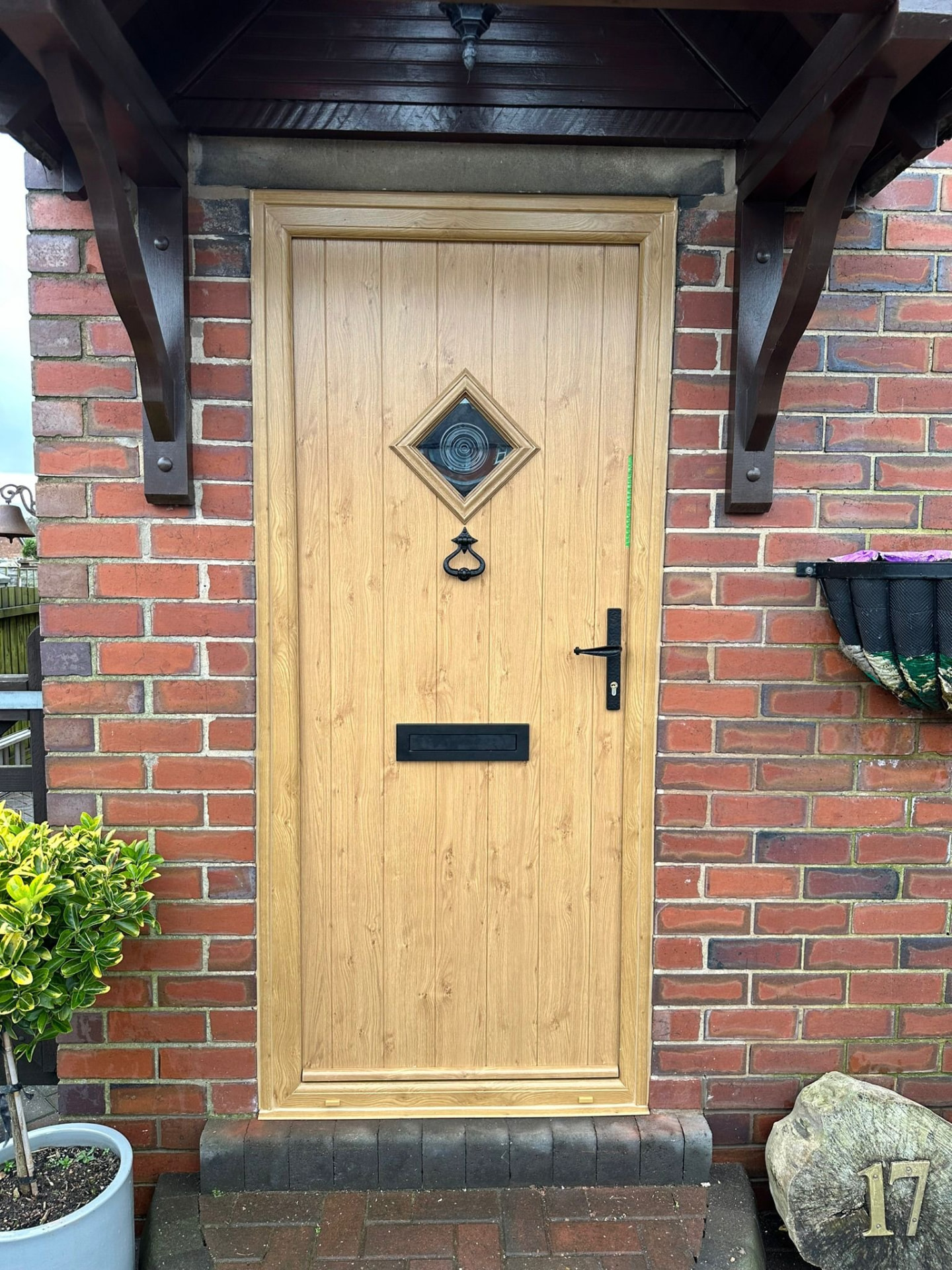 Light oak wood-effect composite door with diamond window and traditional black hardware