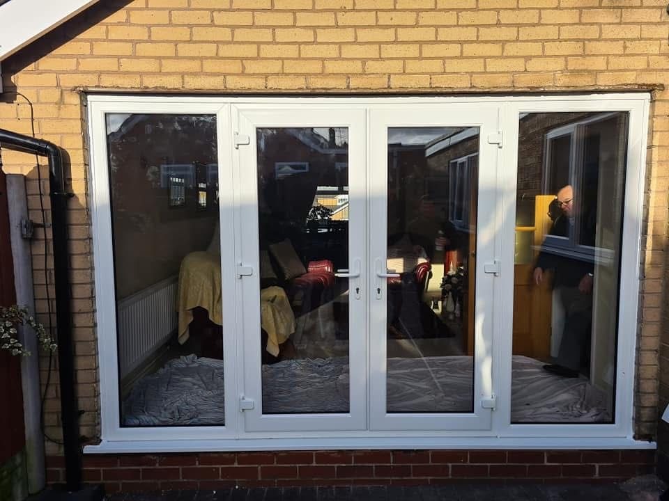 White uPVC French doors with large side panes installed into a brick opening