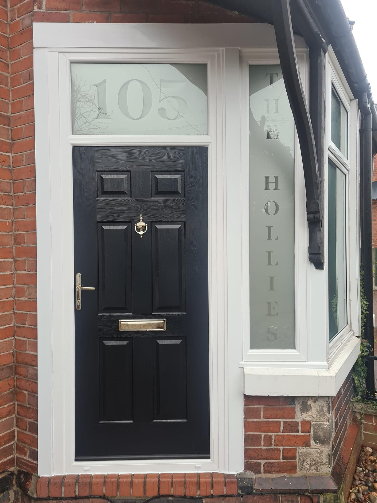 Black six-panel composite door with etched house name and number in the transom panel
