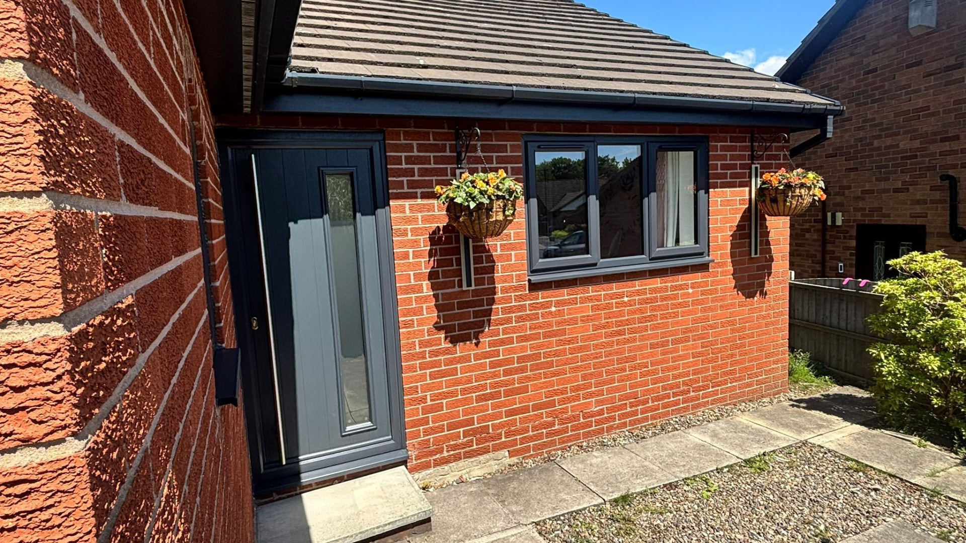 Anthracite grey composite door and matching uPVC window fitted to a red brick bungalow