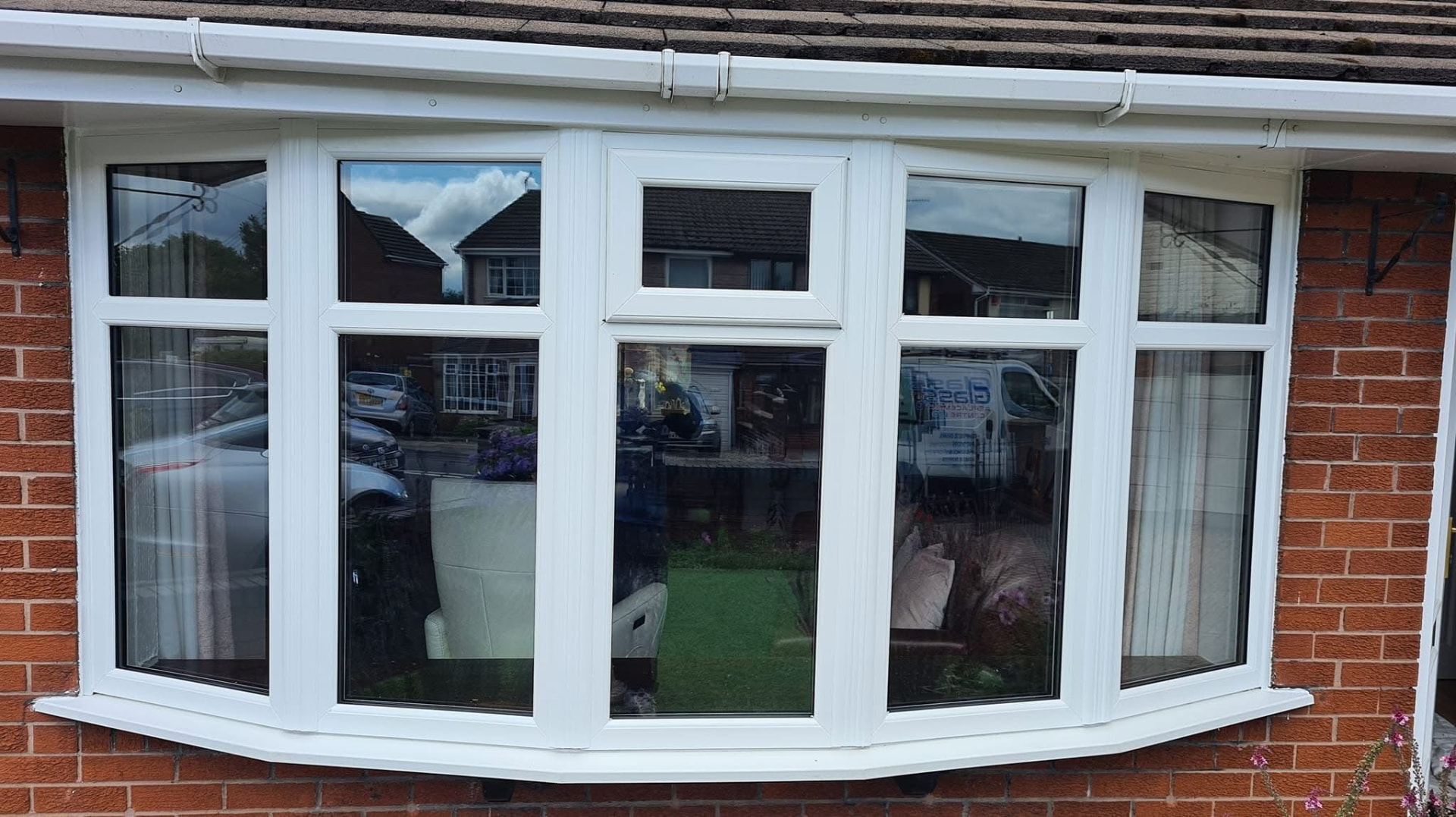 White uPVC bow window with opening top vents fitted to a brick bungalow