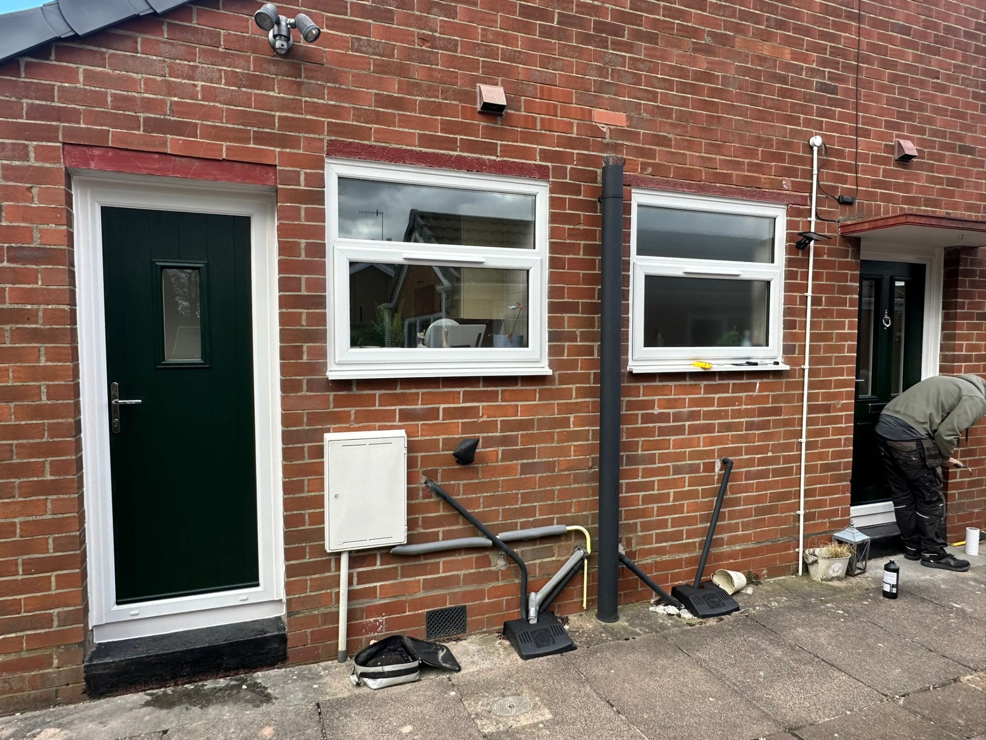 New white uPVC top-hung windows and dark green composite door on a brick property