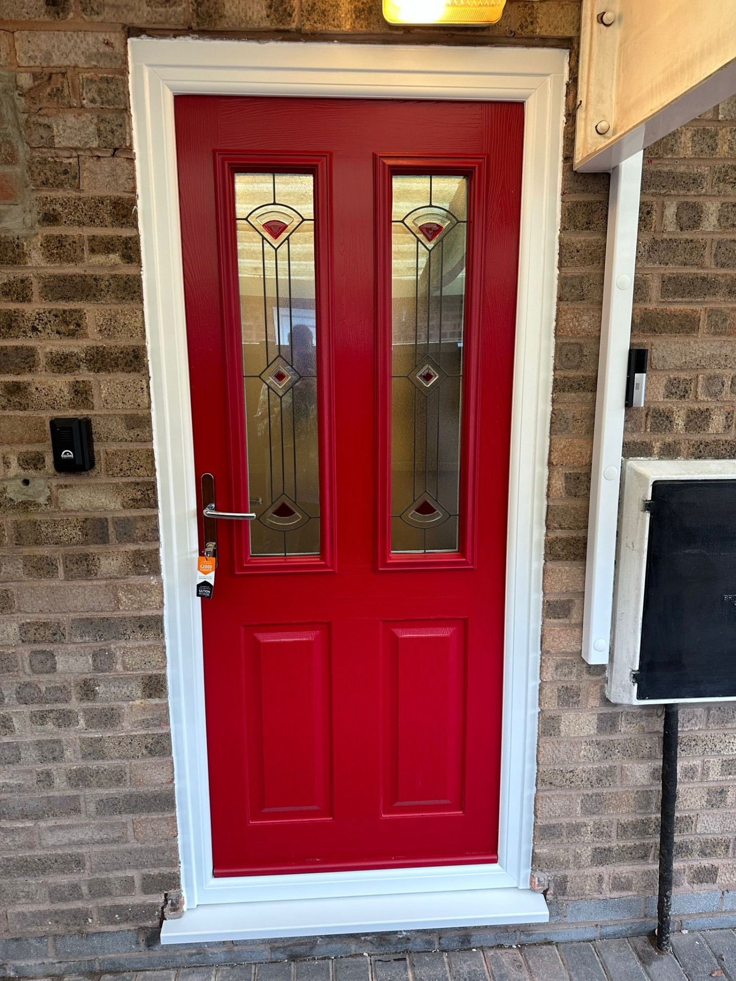 Bright red composite front door with two vertical decorative glass panels fitted in Cheshire