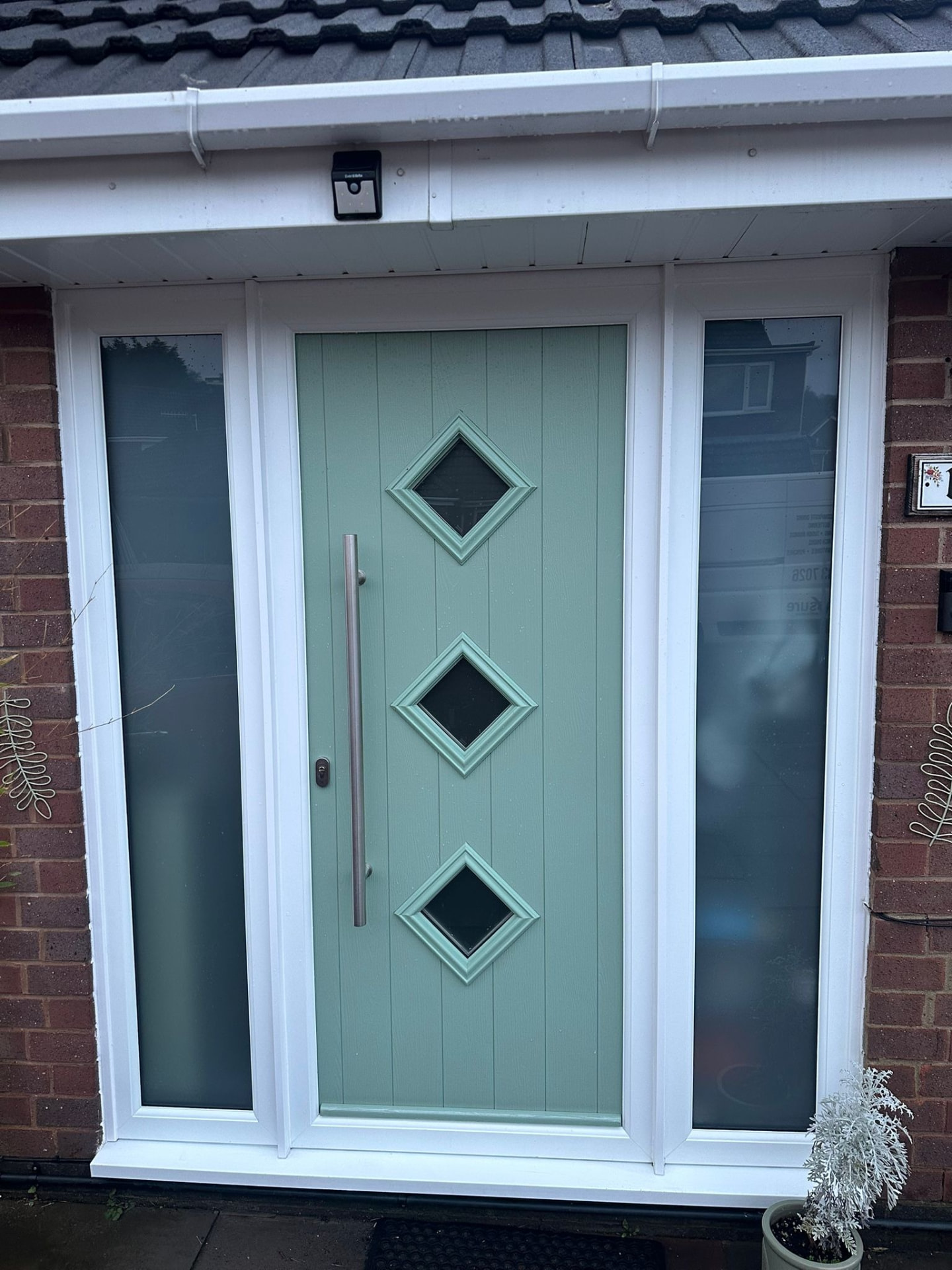 Modern mint green composite door with three diamond windows and stainless steel bar handle