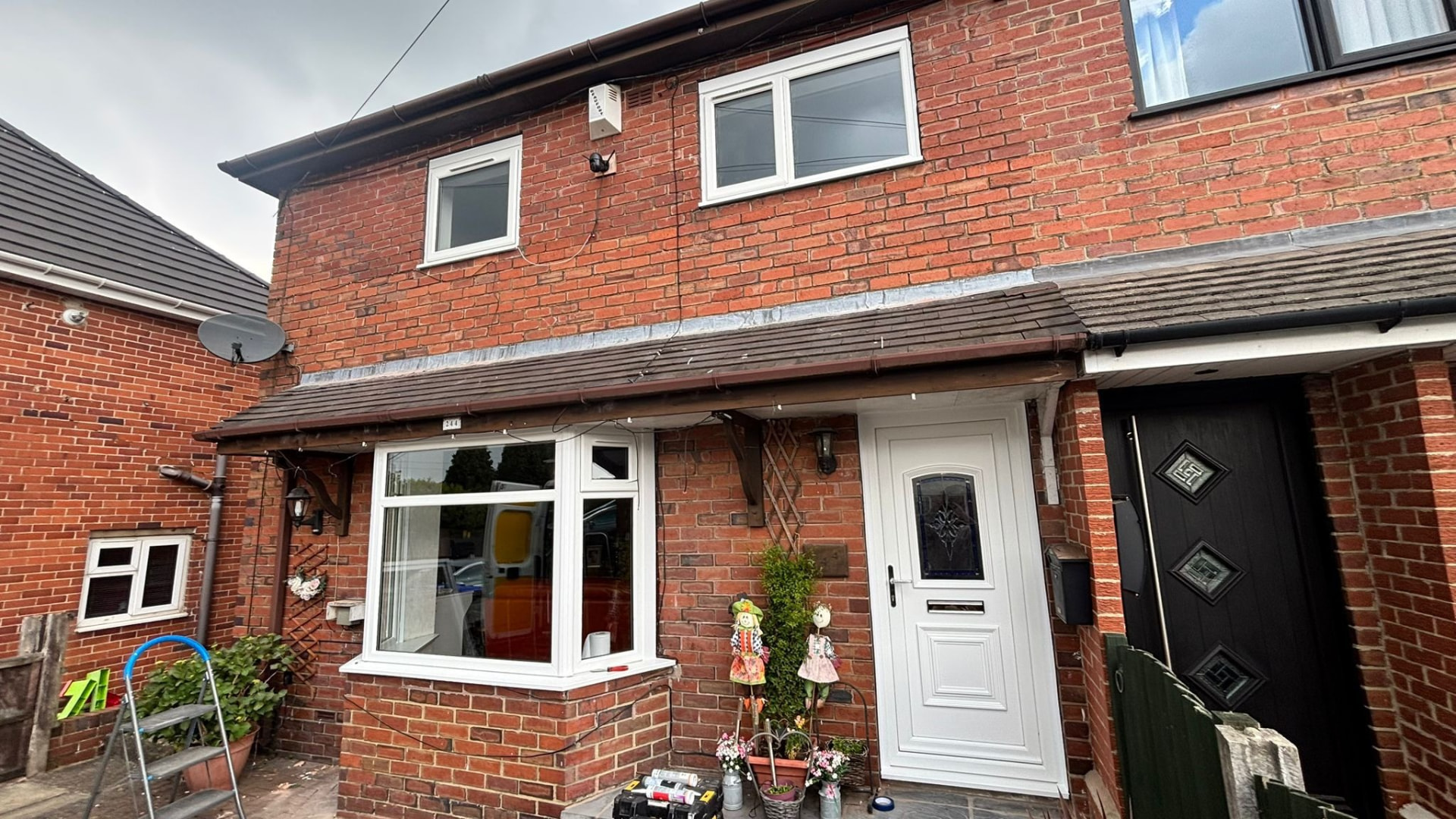 White composite door with decorative arched window fitted beside a replacement bay window