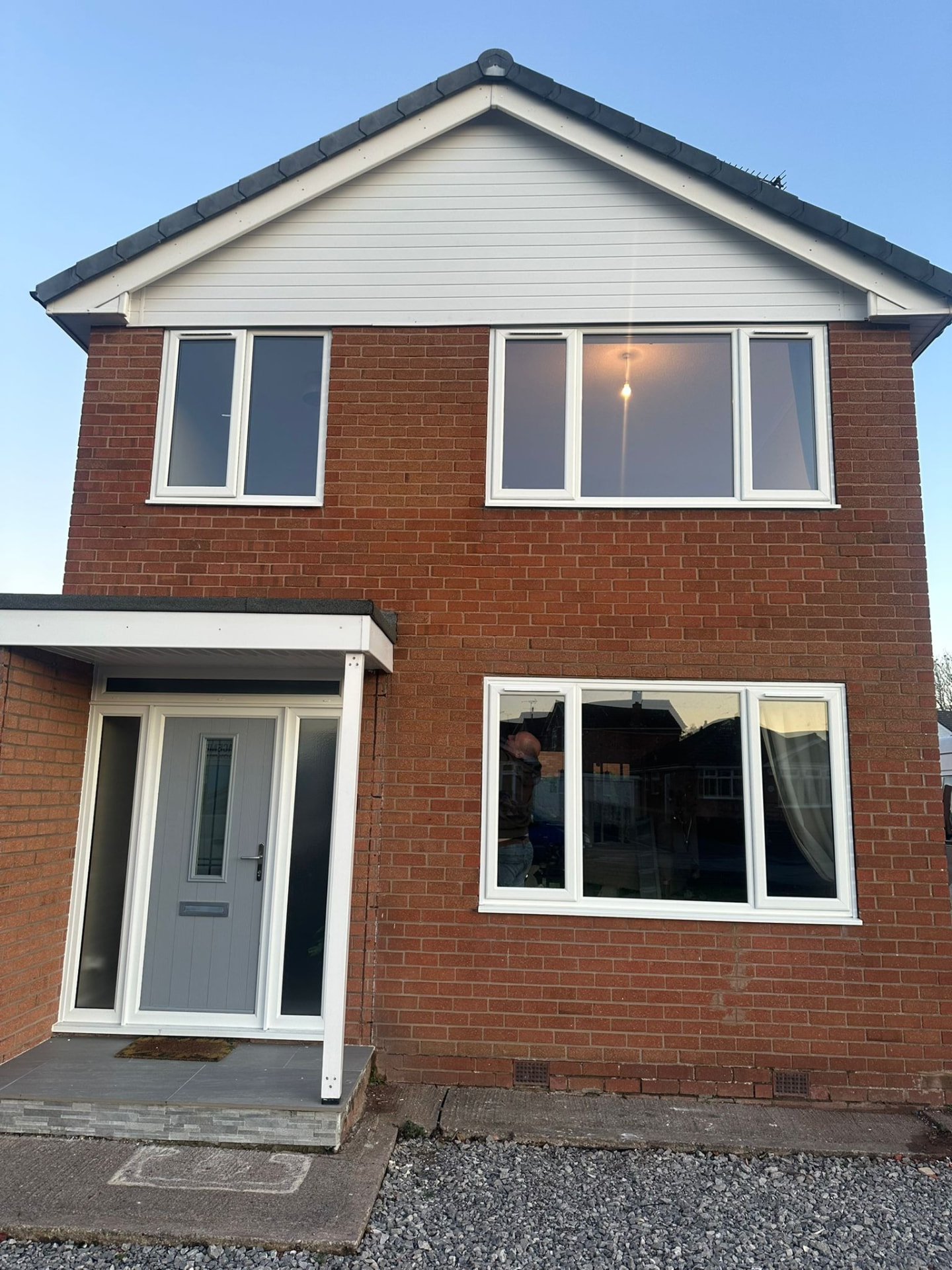 Detached brick house with white uPVC windows and grey composite front door